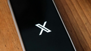in this pic a smartphone on the table in which logo of X shows